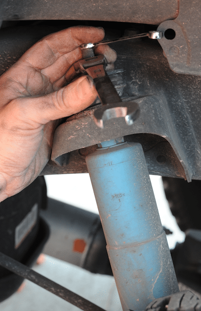 You need two wrenches for the upper shock nut removal. You should also take note during this time of the nut-washer-bushing-vehicle-bushing-washer order used on the top of the shock to locate it to the vehicle.