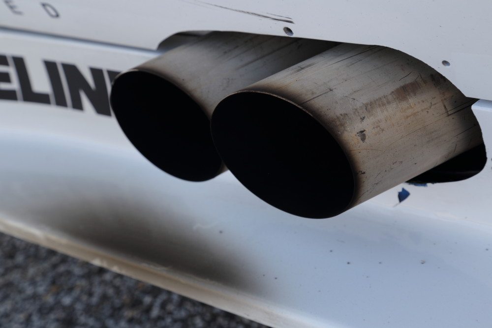 If the exhaust is aimed sideways out the side of the car, the exhaust plume adds a fair amount of unnecessary drag, but if it is located well, it can reduce pressure under the car.
