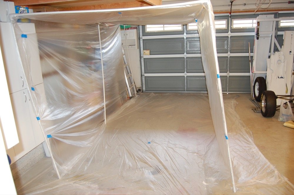 If you have a garage bay that you need to convert to a paint booth, all you need is a big roll of wide, clear plastic sheet from your local paint supply store, several lengths of PVC plastic pipe, and several three- and four-way elbow fittings for them. Three-quarter-inch PVC pipe is the smallest size that will make a self-supporting frame. Half-inch can just barely be made to work by leaning the frame against a wall. Start by taping a sheet of plastic on the floor, then dry assemble the PVC frame without any adhesive. Drape plastic sheet over the top and all sides of the frame, and you have created a non-ventilated paint booth. Use a good painting respirator and take a breathing break every few minutes. 